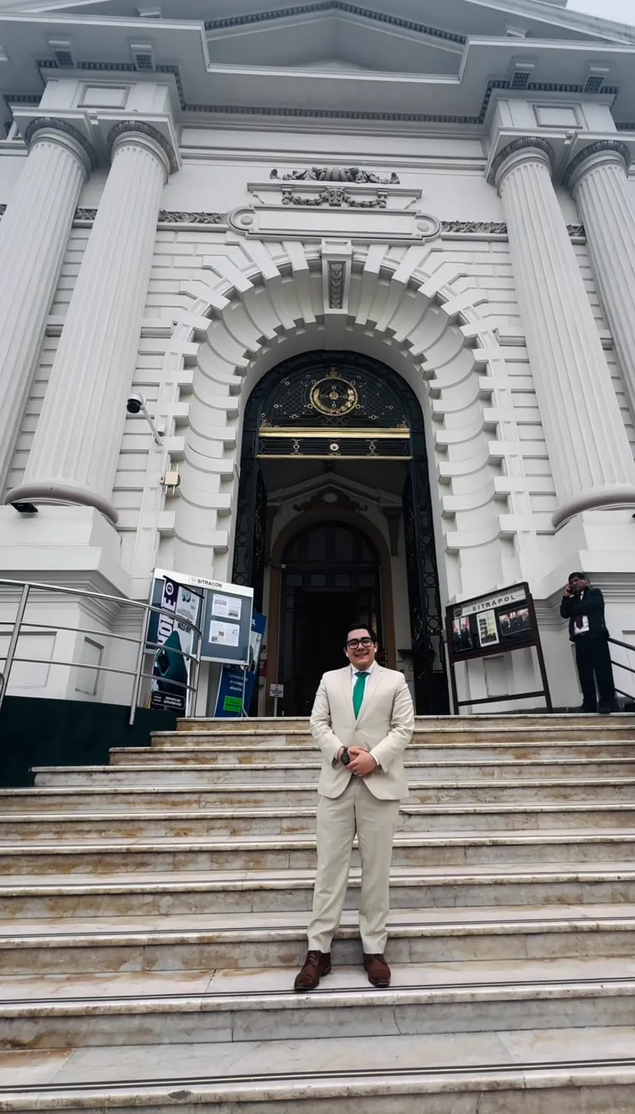 A man in a light suit at the entrance of a public building